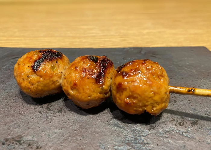 Three balls of grilled meat are served on a skewer at Yakitori Sei.